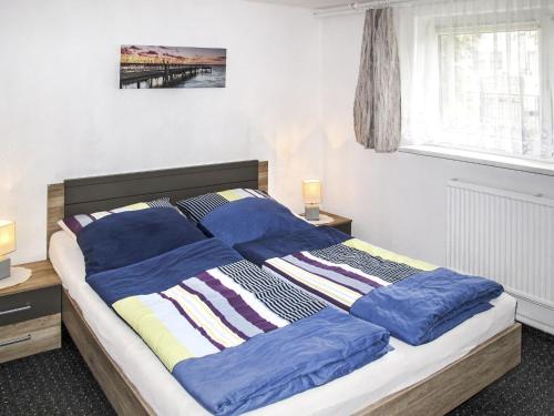 een slaapkamer met een bed met blauwe lakens en een raam bij Apartment Kristin by Interhome in Zinnowitz