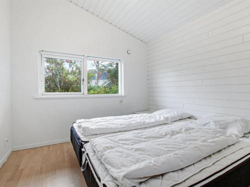 uma cama num quarto branco com uma janela em Holiday Home Majvor - 200m from the sea in NE Jutland by Interhome em Hadsund
