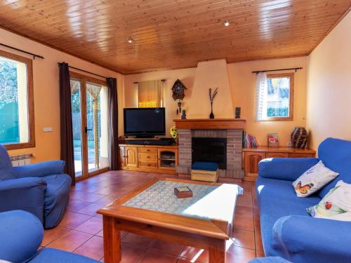sala de estar con sofás azules y TV en Holiday Home La font dels tres pins by Interhome, en Caldes de Malavella