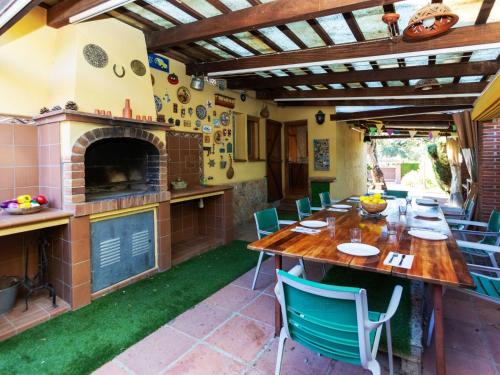 una cocina al aire libre con mesa de madera y sillas en Holiday Home La font dels tres pins by Interhome, en Caldes de Malavella