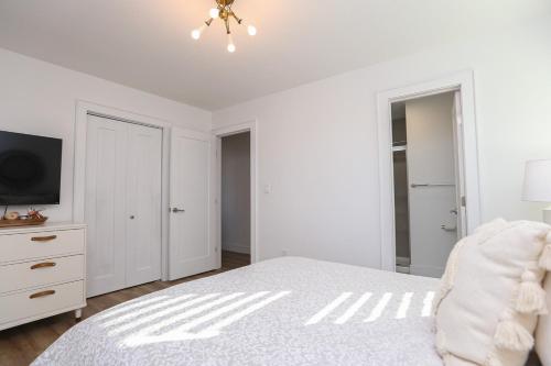 a white bedroom with a bed and a tv at Duck N Cover in Duck