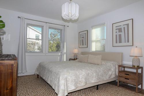 a bedroom with a bed and two windows and a chandelier at Duck N Cover in Duck