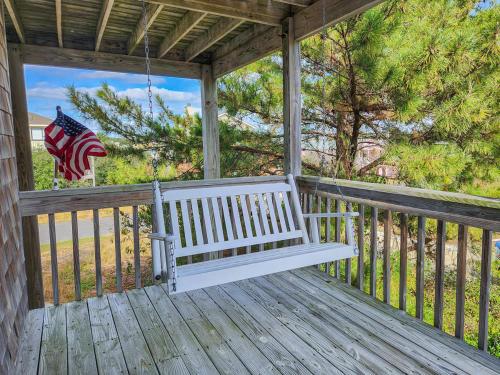 a white bench on a porch with an american flag at Duck N Cover in Duck