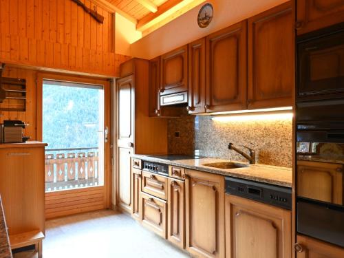 d'une cuisine avec des placards en bois, un évier et une fenêtre. dans l'établissement Apartment Tourbillon B 31 by Interhome, à Ovronnaz
