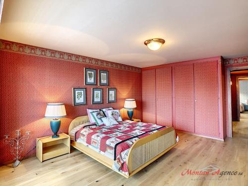 a bedroom with red walls and a bed with two lamps at Apartment Crans-Colline 17 by Interhome in Crans-Montana