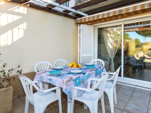 een tafel met witte stoelen en een fruitschaal erop bij Villa Tres calas 2 by Interhome in L'Ametlla de Mar