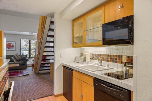 a kitchen with a sink and a living room at Palisades Tahoe Lodge Rentals Studio Loft #305 in Olympic Valley