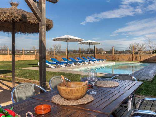 una mesa de madera con copas de vino junto a una piscina en Holiday Home Can Borni by Interhome, en Vidreres