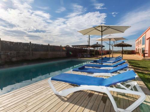 a row of lounge chairs and umbrellas next to a swimming pool at Holiday Home Can Borni by Interhome in Vidreres
