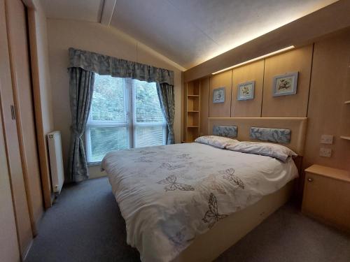 - une chambre avec un grand lit et une fenêtre dans l'établissement Winnie - Caravan mit Meerblick, à Drummore