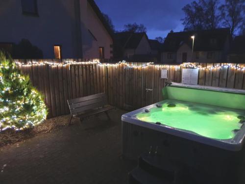 a hot tub with a christmas tree next to a fence at Villa Craigmore Lodge by Interhome in Aviemore