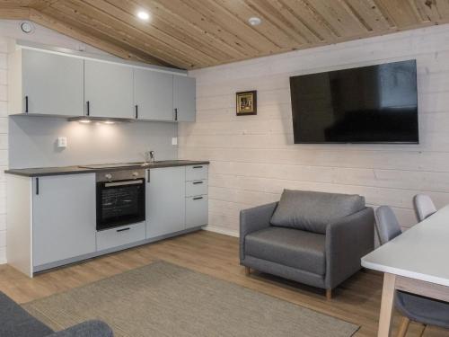 eine Küche mit einem TV, einem Sofa und einem Stuhl in der Unterkunft Holiday Home Pikkuporo f by Interhome in Saariselkä