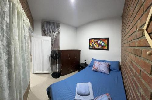 Un dormitorio con una cama azul y una pared de ladrillo en Apartamentos ANGEL'S, en Buga