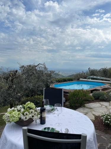 a table with wine glasses and flowers on it with a pool at Podere il Poggio in Avaglio