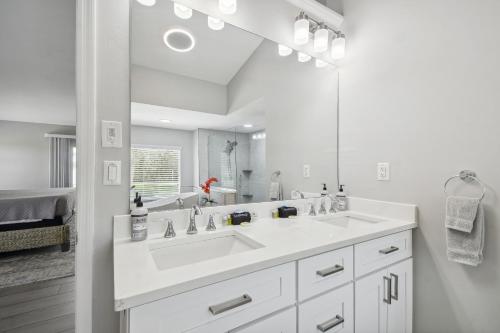 Baño blanco con lavabo y espejo en Lake House Westchase area. Heated Pool Waterfront! en Tampa