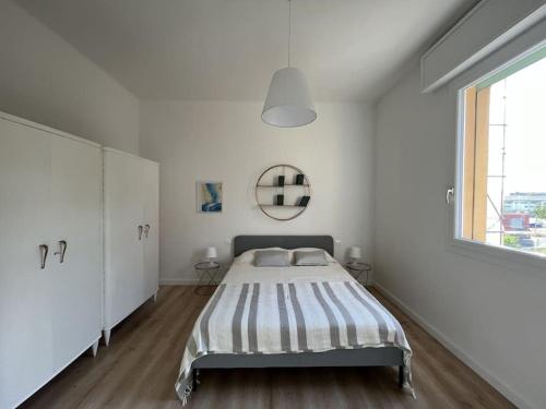 een witte slaapkamer met een bed en een raam bij casa Fioravanti in Bologna