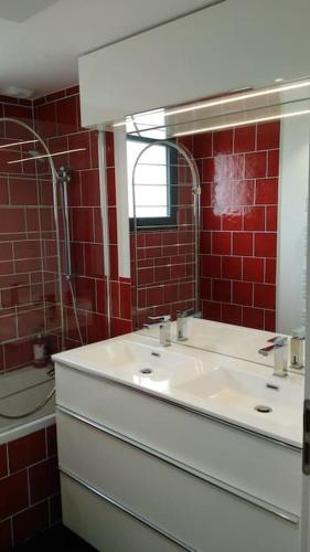La salle de bains est pourvue d'un lavabo blanc et de carreaux rouges. dans l'établissement Villa aux portes de la presqu'ïle de Crozon, à Plomodiern