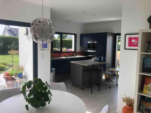 une cuisine et un salon avec une table blanche et un lustre dans l'établissement Villa aux portes de la presqu'ïle de Crozon, à Plomodiern