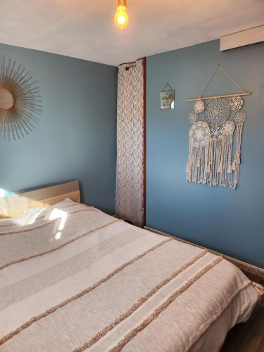 a bedroom with a bed with a blue wall at La Villa du MOULIN DE MADAME in Bias