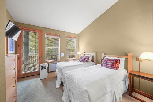 two beds in a room with two windows at Palisades Tahoe Lodge Rentals Two Bedroom #804 in Olympic Valley