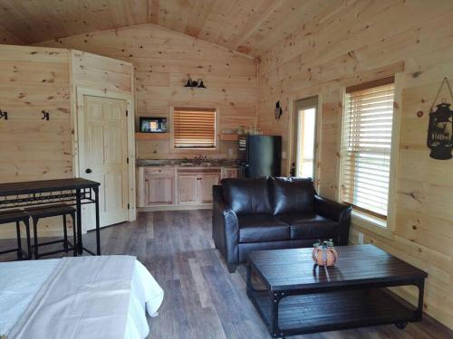 Zimmer mit einem Bett, einem Sofa und einem Tisch in der Unterkunft Cozy Cabin - New Tiny Cabin with Hot Tub/Fire Pit in Sevierville