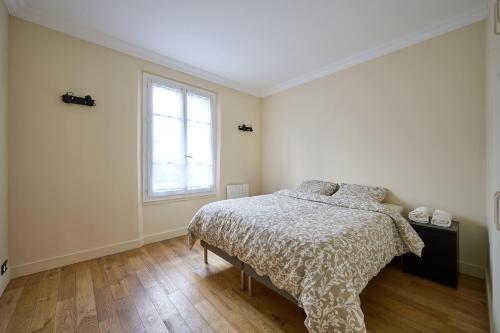 Habitación blanca con cama y ventana en Le Refuge Parisien, en Montrouge