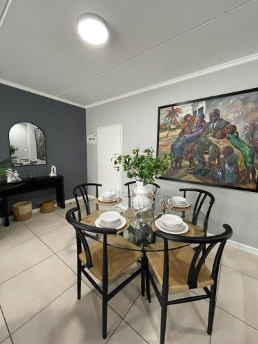 een eetkamer met een tafel en stoelen en een schilderij bij Apartment in Kyalami/Midrand. in Midrand