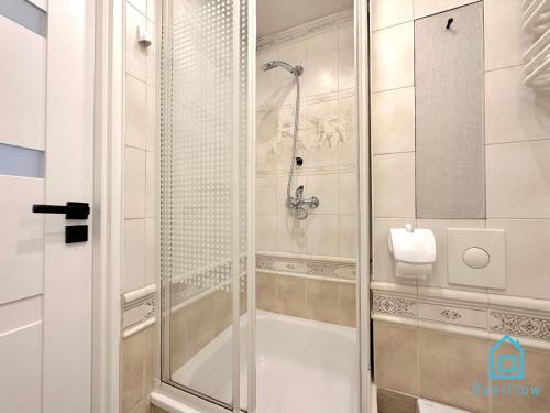 a shower with a glass door in a bathroom at Honey Apartment in Gdańsk