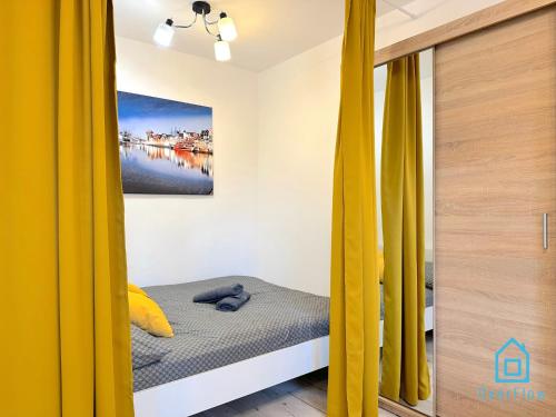a bed with yellow curtains in a room at Honey Apartment in Gdańsk