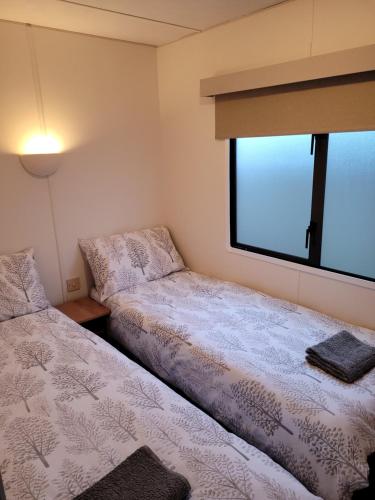Duas camas num pequeno quarto com uma janela em Badgers Rest Loddon em Norwich