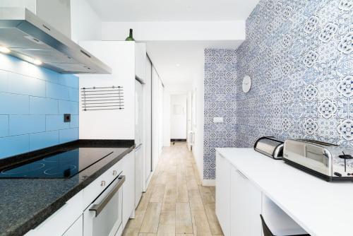 a kitchen with white cabinets and blue tiles at Neptuno Ático, con terraza in Granada