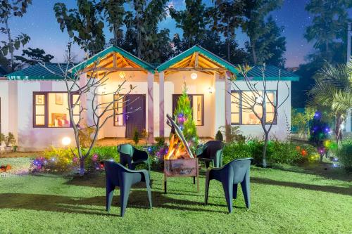 a house with chairs in the front yard at Corbett Mid Forest House in Rāmnagar