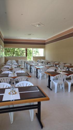 a dining room filled with tables and white chairs at Pousada Vida feliz in Águas de Lindoia