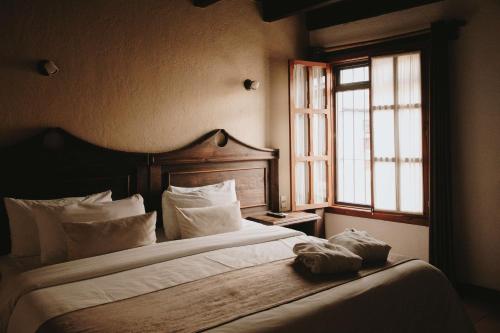 a bedroom with a bed with white pillows and a window at Docecuartos Hotel in San Cristóbal de Las Casas