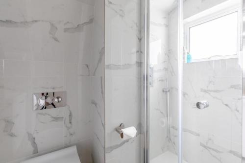 a white bathroom with a shower and a toilet at Sleek & Well-Connected Studio Flat Archway! in London