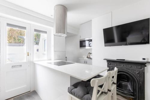 a white kitchen with a white counter and a fireplace at Sleek & Well-Connected Studio Flat Archway! in London