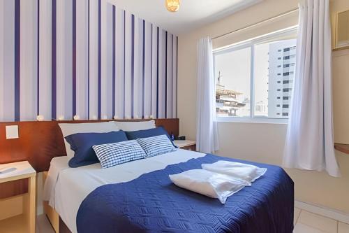 a bedroom with a blue and white bed with a window at Estúdio Próximo a Beira Mar in Florianópolis