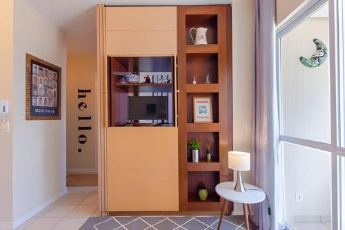 a living room with a book shelf with a tv at Estúdio Próximo a Beira Mar in Florianópolis