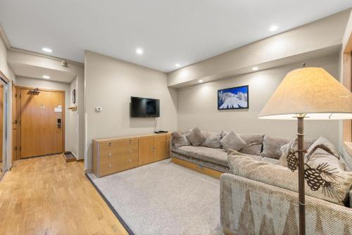 a living room with a couch and a flat screen tv at Palisades Tahoe Lodge Rentals Studio #211 in Olympic Valley