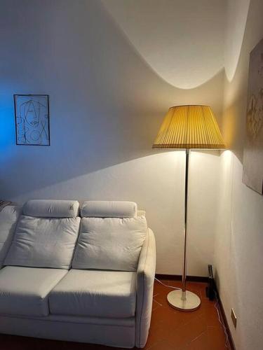 a living room with a white couch and a lamp at Appartamento Ilesis in San Casciano in Val di Pesa