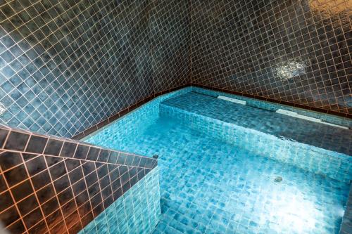 ein Badezimmer mit einer Badewanne mit blauen Fliesen in der Unterkunft Hotel Restaurant zur Sonne St. Peter in Sankt Peter