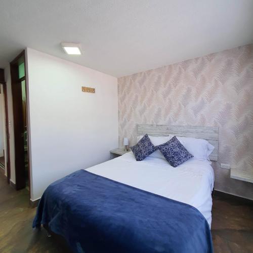 a bedroom with a white bed with blue pillows at La Huerta Hotel Boutique in Tibasosa