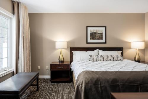 um quarto de hotel com uma cama e duas lâmpadas em Horseshoe Valley Suites - The Glade em Shanty Bay