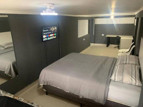 um quarto com uma cama e uma televisão na parede em Loft Eco City 02-Espaçoso e Confortável c/ Garagem em Curitiba