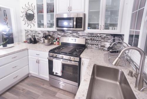 a kitchen with white cabinets and a stove and a sink at Blanquitas Home in Long Beach