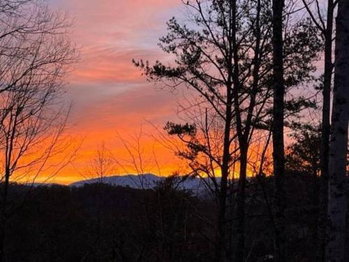 a sunset in the mountains with trees in the foreground at Robin's Roost in Sevierville