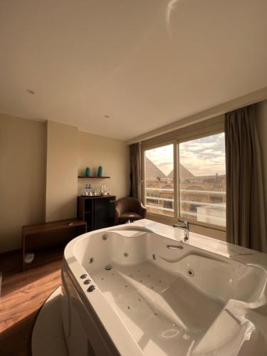 una grande vasca da bagno in una stanza con una grande finestra di The Home Boutique Hotel Pyramids Inn a Il Cairo