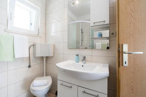 La salle de bains blanche est pourvue d'un lavabo et de toilettes. dans l'établissement Holiday Home Ivona, à Vela Luka