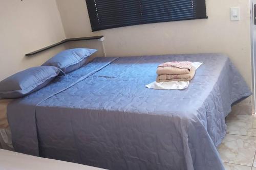 a bed with blue sheets and pillows on it at Mini Casa em Arraial d'Ajuda in Porto Seguro
