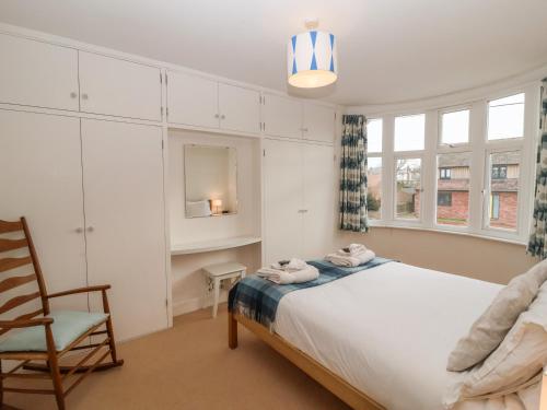 a bedroom with a bed and a chair and a window at Sailors Rest, Southwold in Southwold
